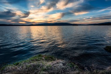 Gölün üzerinde büyüleyici bir günbatımı ve suyun üzerinde güzel bir yansıması var. Mavi saatte dingin göl. Doğa manzarası