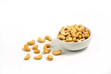 Beyaz arka planda izole edilmiş seramik bir kasede çiğ kaju fıstığı. Kavrulmuş kaju fıstığı