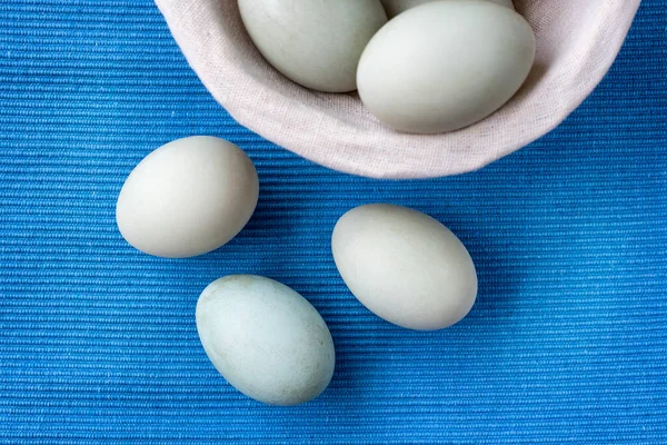 Fresh duck eggs collect from farm products natural in a wicker basket healthy eating concept. blue cloth background