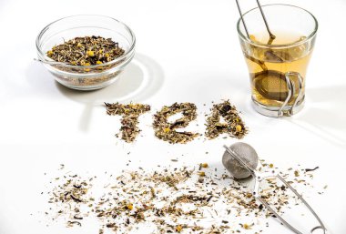 Beyaz arka planda çay yaprağı tarafından bir kase çay ve küçük cam çay fincanı ile yapılan çay metni