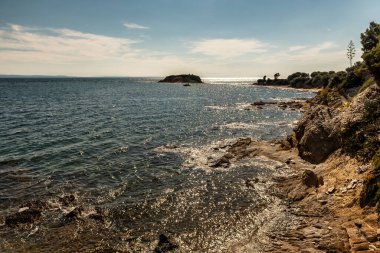 Kayalık sahil dalgalarının deniz burnu kayalara çarpar ve suya düşer. Deniz manzarası, okyanus. Doğal yumuşak mavi arkaplan.