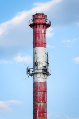 Mavi gökyüzünün arka planında beyaz ve kırmızı baca. Elektrik santrali bacası.