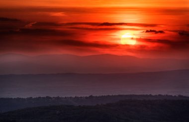 Tepelerin ve dağların katmanlarıyla gün batımı, yumuşak odaklanma. Gün batımında dağ katmanları. Mavi dağlar ve son güneş ışığı manzarası.