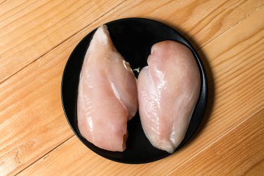 Izgara için siyah tabakta tavuk filetosu hazır. Pişirmek için tavuk bifteği. Üst görünüm