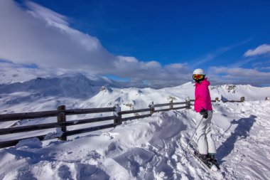 Parlak kış kıyafetleri giymiş bir kayakçı.