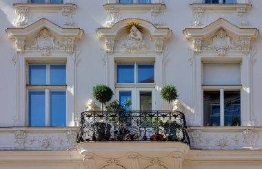 Klasik beyaz Viyana cephesinde süslü bir demir balkon.