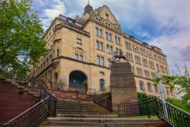 Basel 'deki Leonhard Spor Salonu klasik mimari, belirgin bir merdiven ve bir heykelin yer aldığı tarihi bir okul binasıdır.