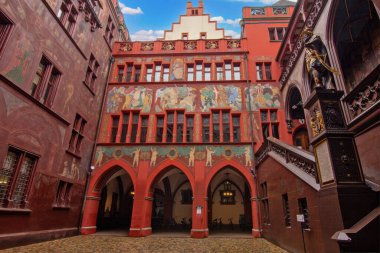 Basel Belediye Binası 'nın iç avlusunda zengin şekilde boyanmış duvarlar, tarihi kemerler, bir saat ve heykel ayrıntıları sergileniyor.,