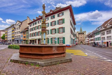 Basel 'de tarihi bir meydan. İçinde dekoratif bir çeşme, geleneksel binalar ve eski kasabadan geçen modern bir tramvay var..
