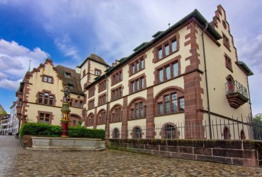 Taş cepheli tarihi bir Basel binası, avlu çeşmesi ve sakin eski kasaba atmosferi..