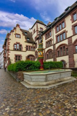 Taş cepheli tarihi bir Basel binası, avlu çeşmesi ve sakin eski kasaba atmosferi..