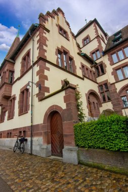 Taş cepheli tarihi bir Basel binası, avlu çeşmesi ve sakin eski kasaba atmosferi..