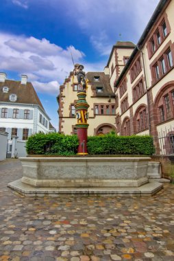 Taş cepheli tarihi bir Basel binası, avlu çeşmesi ve sakin eski kasaba atmosferi..