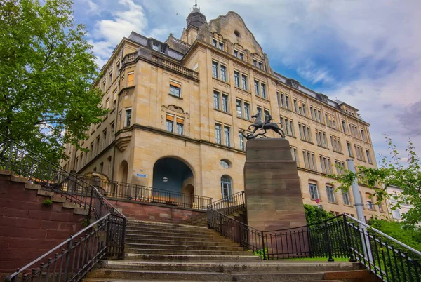 Basel 'deki Leonhard Spor Salonu klasik mimari, belirgin bir merdiven ve bir heykelin yer aldığı tarihi bir okul binasıdır.