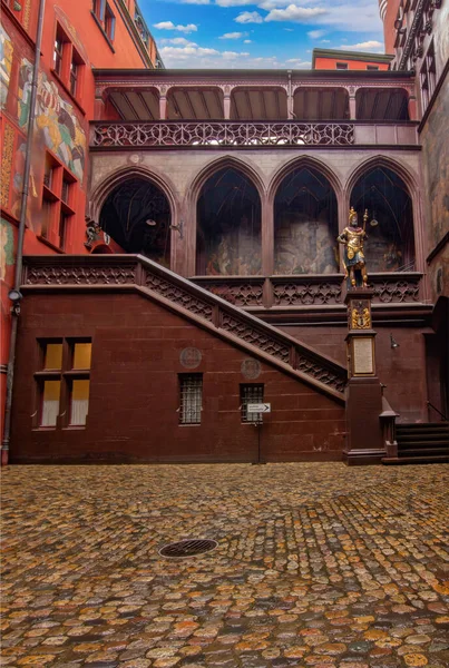 Basel Belediye Binası 'nın iç avlusunda zengin şekilde boyanmış duvarlar, tarihi kemerler, bir saat ve heykel ayrıntıları sergileniyor.,