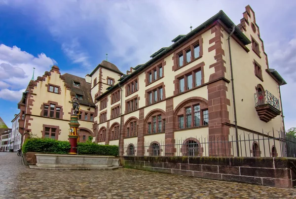 Taş cepheli tarihi bir Basel binası, avlu çeşmesi ve sakin eski kasaba atmosferi..