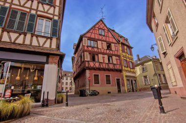 Colmar 'da sakin bir kaldırım taşı meydanı etrafında tarihi renkli kereste evler..