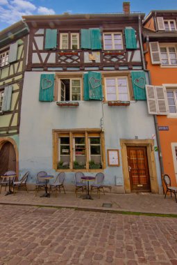 Colmar 'da sakin bir kaldırım taşı meydanı etrafında tarihi renkli kereste evler..