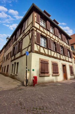 Colmar 'da sakin bir kaldırım taşı meydanı etrafında tarihi renkli kereste evler..