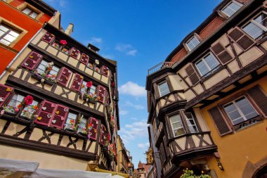 Colmar 'da dar bir sokakta çiçeklerle kaplı renkli tarihi kereste evleri..