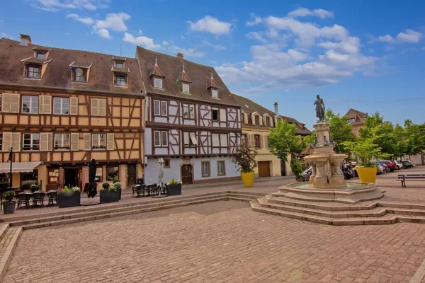 Colmar 'da sakin bir kaldırım taşı meydanı etrafında tarihi renkli kereste evler..