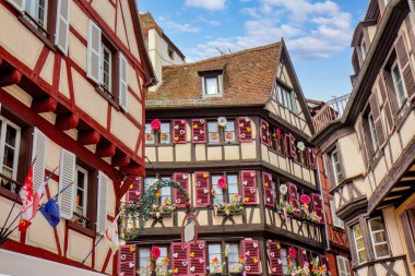 Colmar 'da büyüleyici dar bir caddede çiçek ve kepenkleri olan parlak tarihi kereste evleri..
