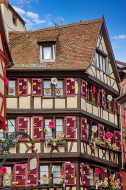 Colmar 'da büyüleyici dar bir caddede çiçek ve kepenkleri olan parlak tarihi kereste evleri..