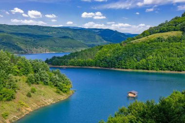 Sırbistan 'ın güneydoğusundaki Pirot yakınlarındaki orman tepeleri ve dağlarla çevrili Zavoj Gölü' nün panoramik manzarası mavi gökyüzünün altında