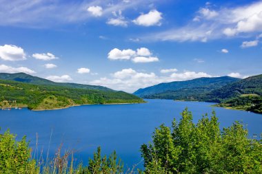 Sırbistan 'ın güneydoğusundaki Pirot yakınlarındaki orman tepeleri ve dağlarla çevrili Zavoj Gölü' nün panoramik manzarası mavi gökyüzünün altında
