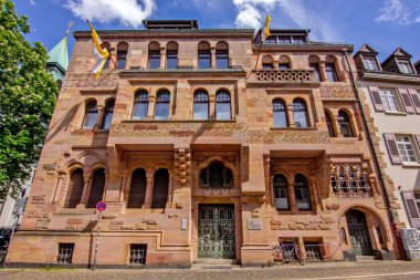 Freiburg im Breisgau 'daki Başpiskopos Ordinarya binasının kemer kolonları, pencereleri ve bayraklarıyla süslü taş cephe