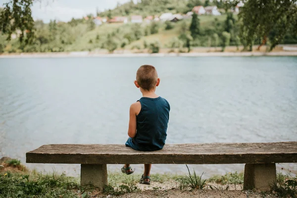 Befelé forduló fiú ül a tó partján — Stock Fotó