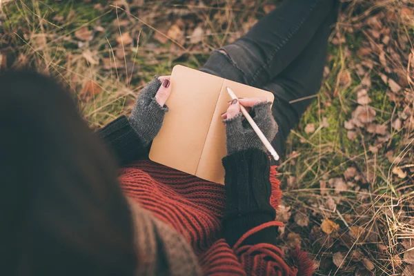 Frau in der Natur schreibt in ein Notizbuch — Stockfoto