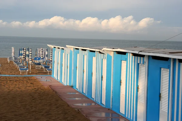 Badehaus mit blauen Kabinen, Liegen und Sonnenschirmen — Stockfoto