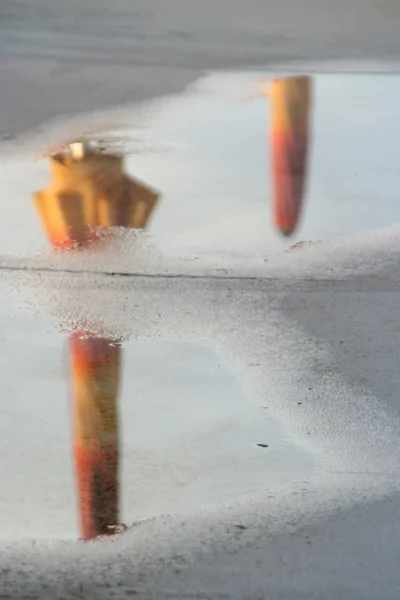 Orange sun umbrellas reflecting in a puddle — Stock Photo, Image