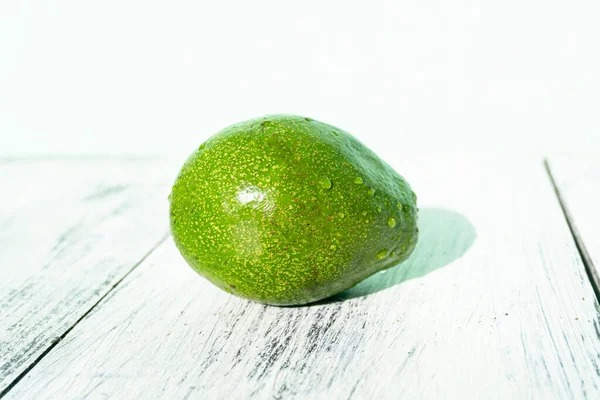 Avocado on a wooden bright background, healthy tropical fruit.