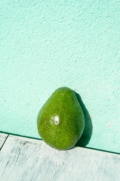 Avocado on a wooden bright background, healthy tropical fruit.