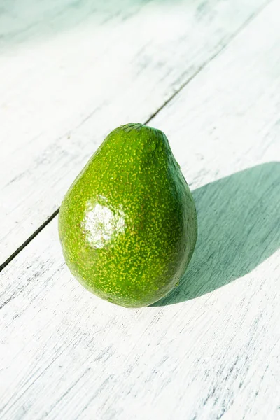 Avocado on a wooden bright background, healthy tropical fruit.