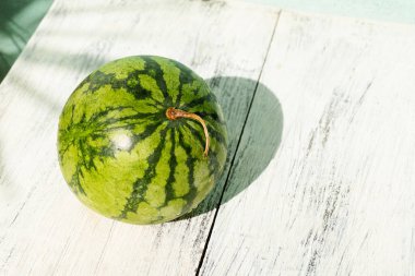 Fresh fruit green watermelon on wooden background in daylight.