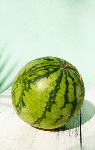 Fresh fruit green watermelon on wooden background in daylight.