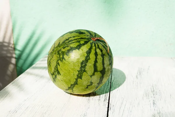 Fresh fruit green watermelon on wooden background in daylight.