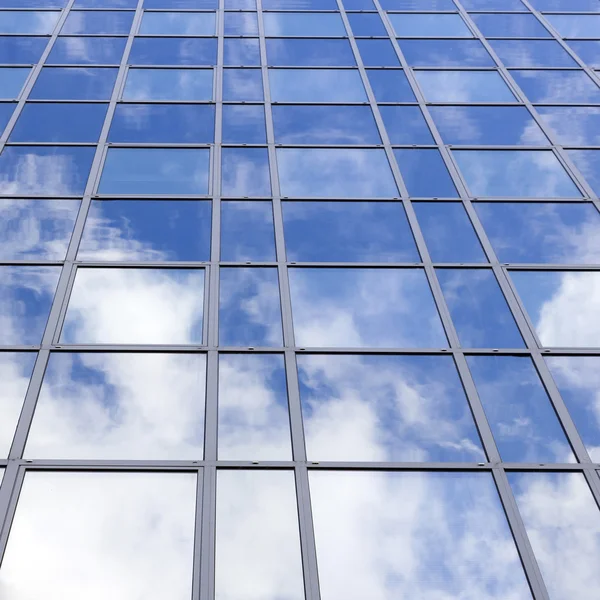 Glass office facade reflects clouds and blue sky — Stock Photo, Image