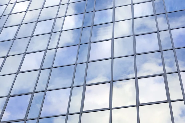 Moderno edificio in vetro con riflessi di cielo blu e nuvole — Foto Stock