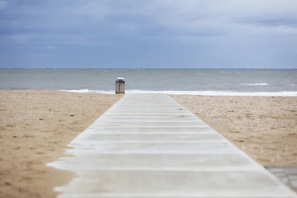 Caminho concreto na praia vazia com lata de lixo e céu nublado — Fotografia de Stock