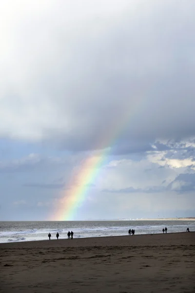 Gente pasea por la playa del mar del norte en Holanda con cielo nublado y — Foto de Stock