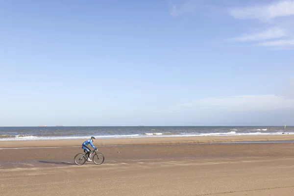 Hombre en bicicleta de montaña en la playa con el cielo azul — Foto de Stock