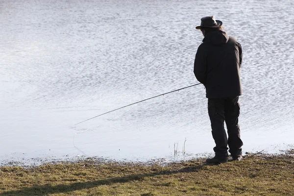 Silhouette eines einsamen Fischers mit Angelrute — Stockfoto
