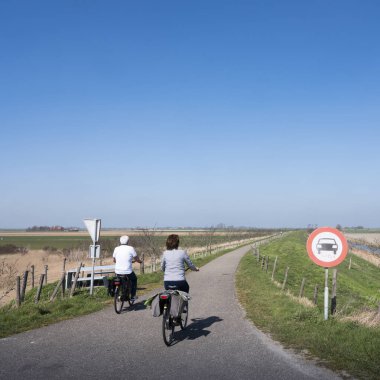 İnsanlar güneşli bir bahar gününde bisiklet sürüyor Hollanda kırsalında mavi gökyüzünün altında