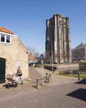 Zierikzee, Hollanda, 30 Mart 2021: Genç kadın eski Zierikzee kentindeki eski bir kulede, mavi gökyüzünün altında bebek arabasıyla yürüyor.