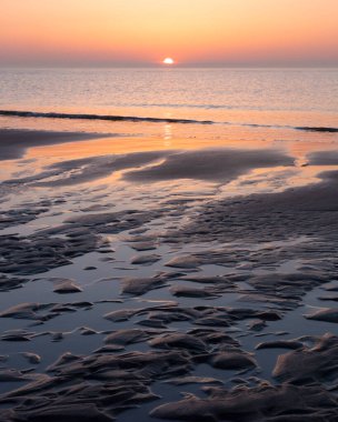Kumda desen ve suda güneşin batışının renkli yansıması