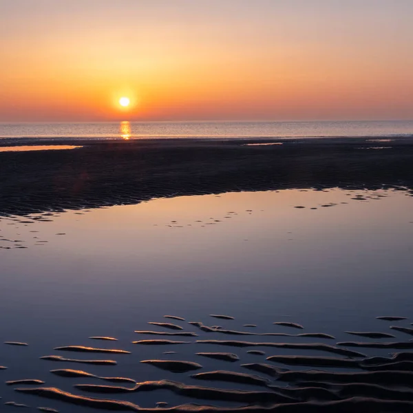 在海滩附近的水中反射着五彩缤纷的落日 — 图库照片